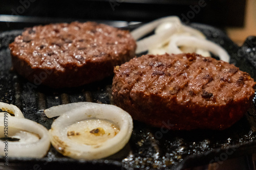 Roasted grilled hamburgers with onions closeup. Dark background.