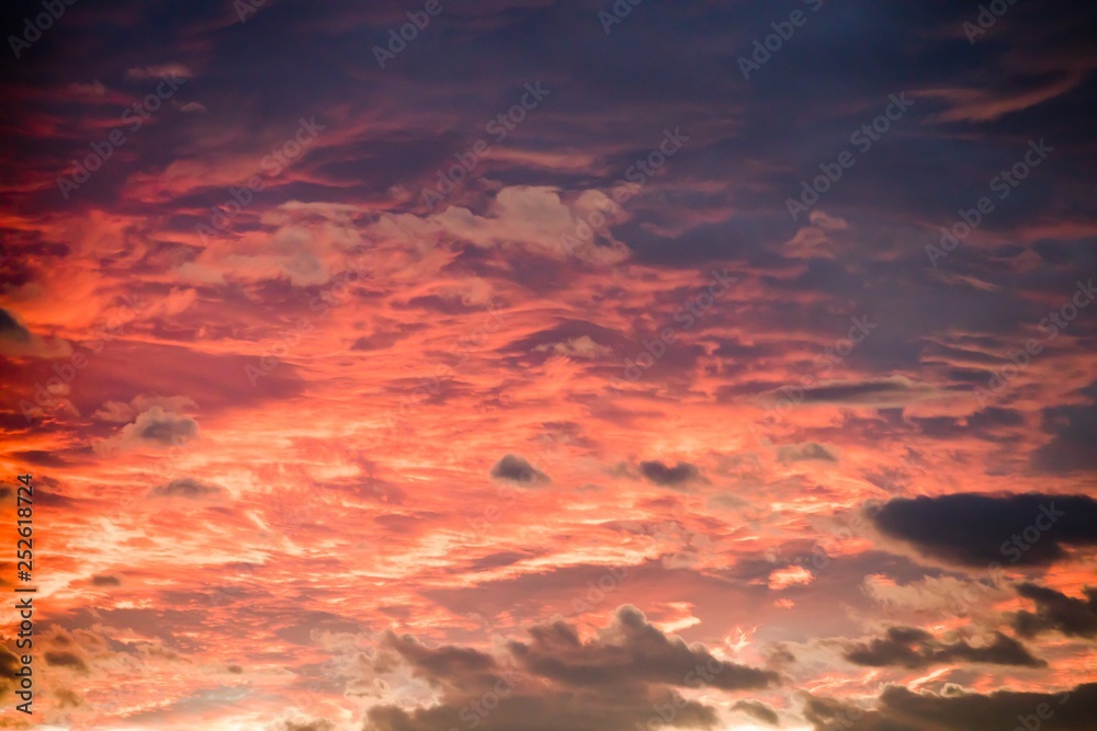 Sunset sky background with fiery clouds, orange and blue colors.