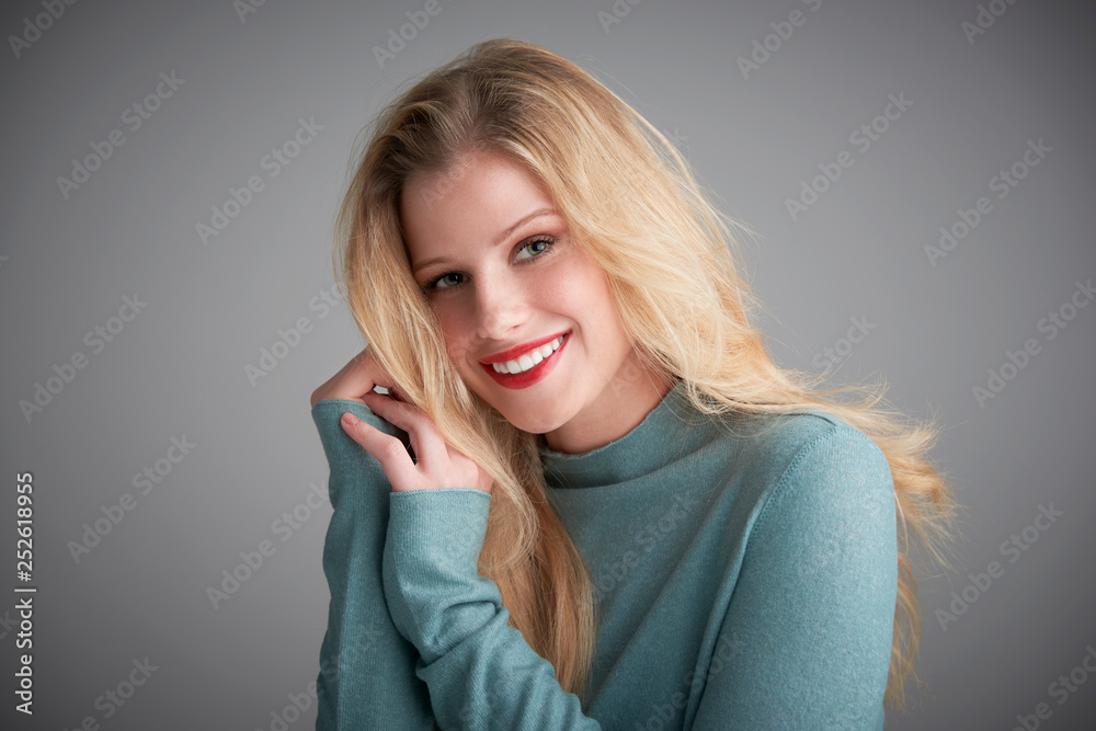 Studio portrait of beautiful young woman looking at camera and smiling Studio portrait of beautiful young woman looking at camera and smiling
