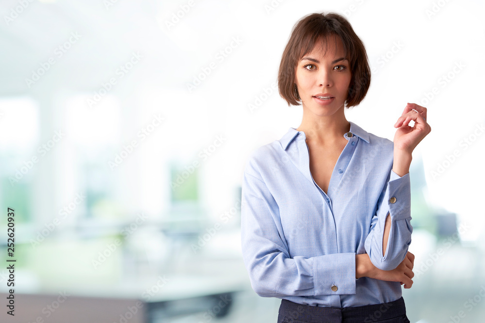 Attracive businesswoman standing with folded arms in the office Attracive businesswoman standing with folded arms in the office