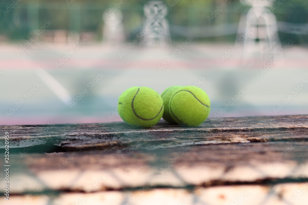 close-up tennis ball on wooden table With blurred tennis court background