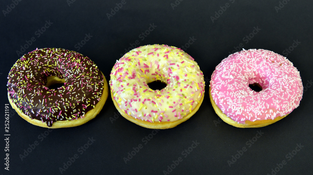 drei verschiedene donuts vor schwarzem hintergrund drei verschiedene donuts vor schwarzem hintergrund