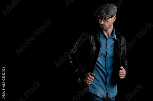 man adjusting his black leather jacket looking away