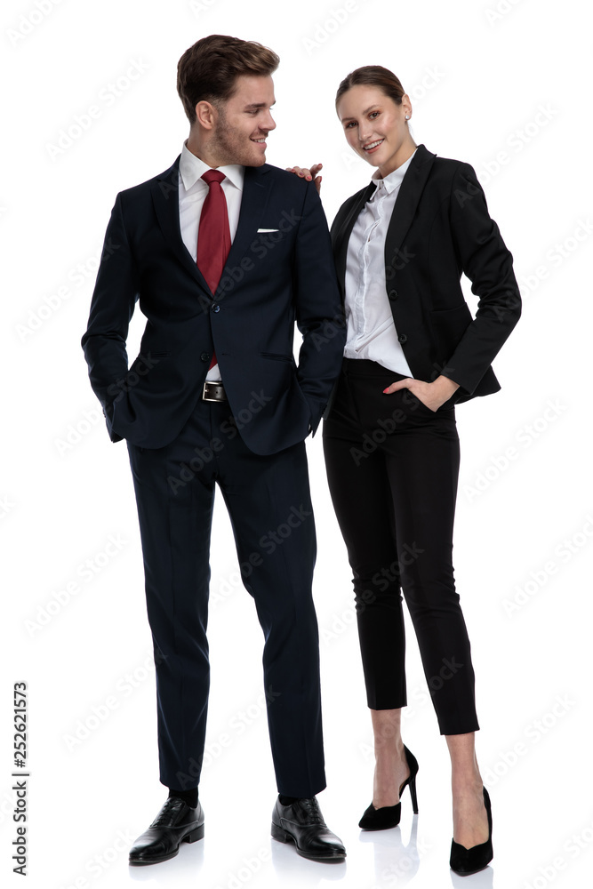 couple in business suits standing together with hands in pockets couple in business suits standing together with hands in pockets