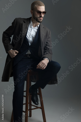 blonde guy sitting on a stool holding his arm on knee