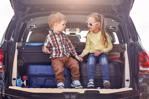 The best education you will ever get is traveling. Little cute kids in the trunk of a car with suitcases. Family road trip
