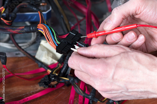 Technician equipment repair. A man checks the electrical power of personal computer. Computer repair process.