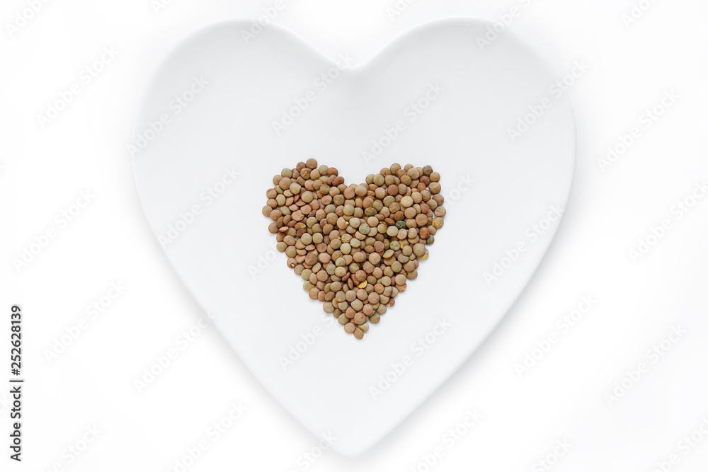 Lentils lie in the shape of a heart on a white plate