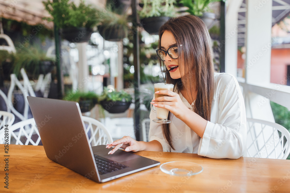 Beautiful girl drinking latte in the cafe in summer day Beautiful girl drinking latte in the cafe in summer day