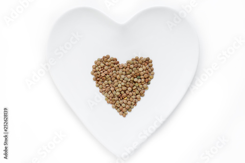 Lentils lie in the shape of a heart on a white plate