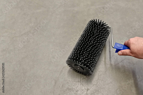 A man holds in his hand a construction roller-building tool for the self-leveling floor