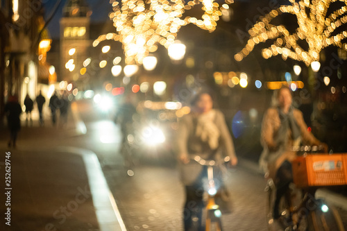 women cyclists ride down the street at night, bokeh and blur