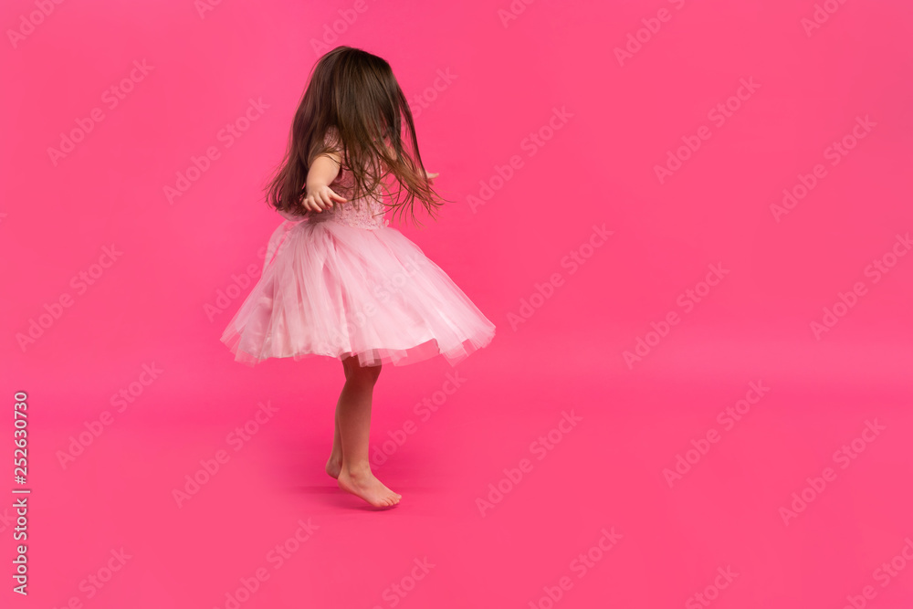 Cute little girl dreams of becoming a ballerina. Little Dancing Girl. Studio Shoot Over Pink Background Cute little girl dreams of becoming a ballerina. Little Dancing Girl. Studio Shoot Over Pink Background