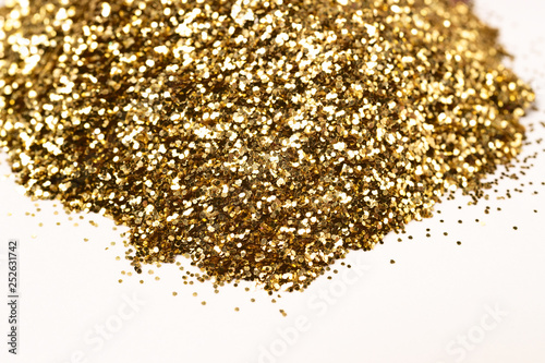 A bunch of golden nail gritter for manicure. Golden glitter shining on daylight. Stock photo isolated on white background. Nail varnish topping.