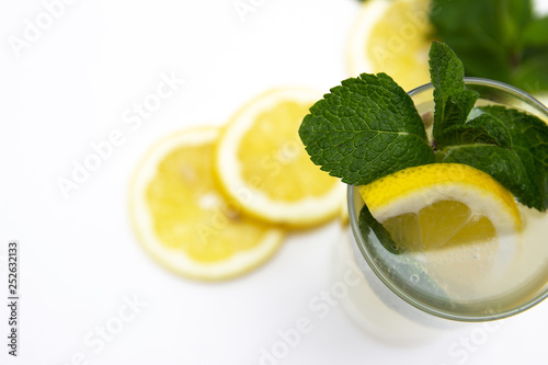 a glass of fresh lemonade, against a background of lemons and mint, isolated on a white background. top view. copy space.