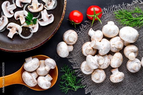 Fresh sliced champignons in a pan. Cooking homemade dishes of white mushrooms with tomatoes cherry, parsley and dill