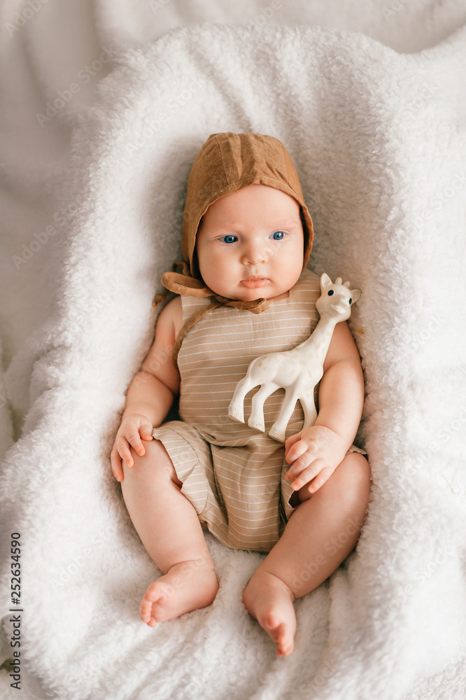Adorable lovely newborn male baby with smiling happy face lifestyle indoor portrait from above. Funny infant child lying with toy in basket covered with white bedspread. Children - flowers of life. Adorable lovely newborn male baby with smiling happy face lifestyle indoor portrait from above. Funny infant child lying with toy in basket covered with white bedspread. Children - flowers of life.