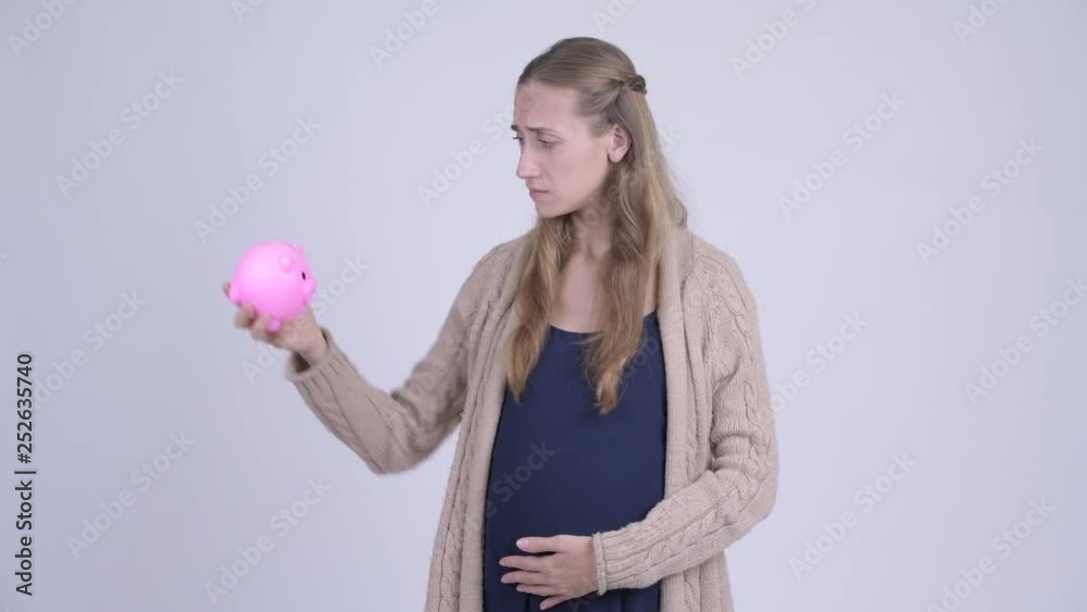 Stressed young pregnant woman holding piggy bank and giving thumbs down Stressed young pregnant woman holding piggy bank and giving thumbs down