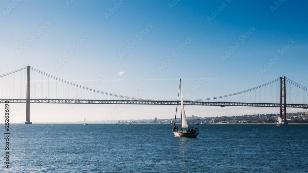 Sailboats with white sails on the Tagus River, 25 of April Bridge, Lisbon, Portugal