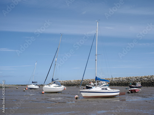 Three small yachts are in the harbor on the ground after the ebb