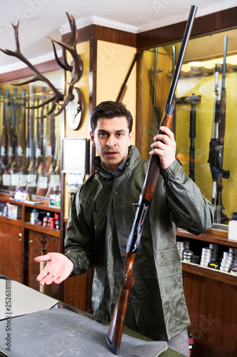 Man choosing rifle in shop