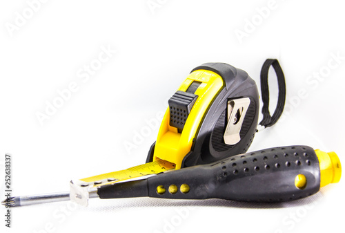 construction tool measuring tape next to screwdriver on white background
