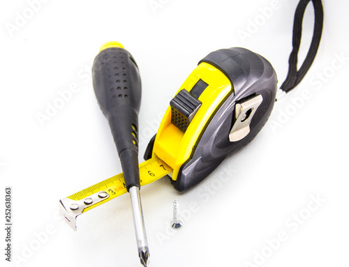 construction tool measuring tape next to screwdriver on white background