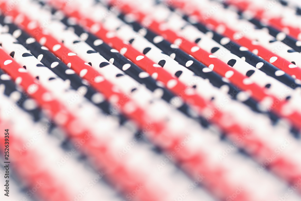 Fototapeta premium Dotted paper straws background close up, trendy coral red white and black with copy space. Beyond plastic concept and pattern