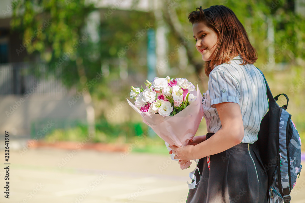 Teen girl holds a bouquet of flowers and goes to school. student congratulates with Women's Day on March 8 teacher. Holidays at school. Birthday at child of 11 years. Teen girl holds a bouquet of flowers and goes to school. student congratulates with Women's Day on March 8 teacher. Holidays at school. Birthday at child of 11 years.