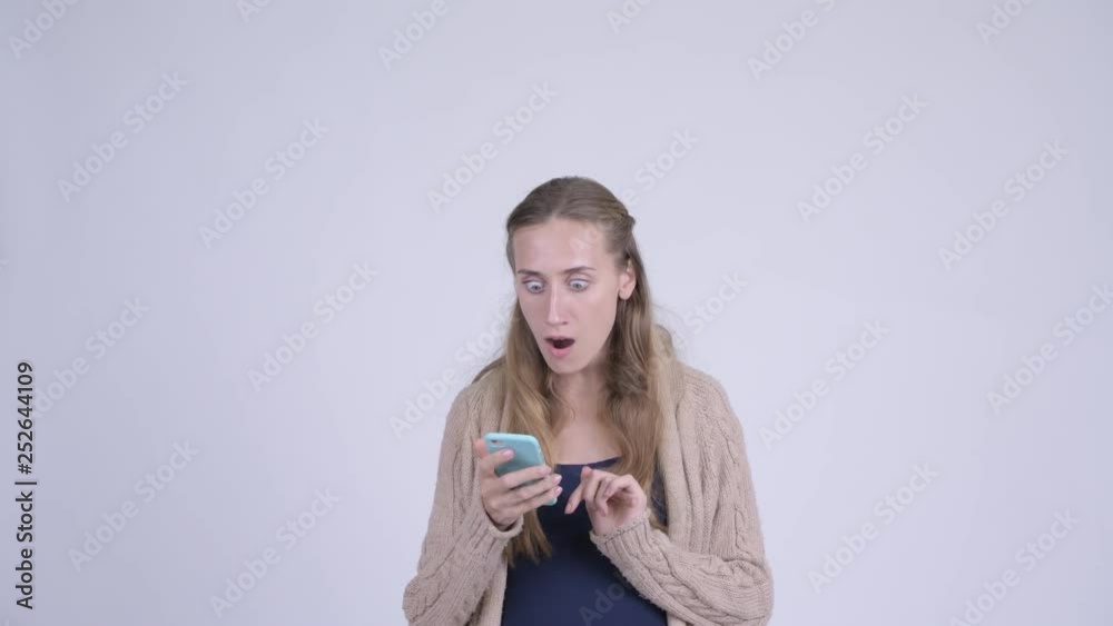 Happy young pregnant woman using phone and looking surprised Happy young pregnant woman using phone and looking surprised