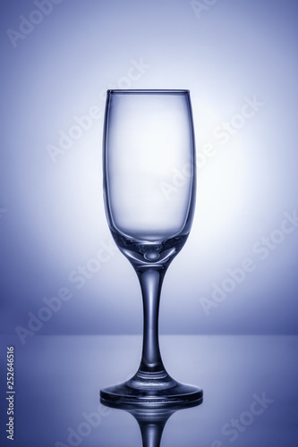 Empty wine glass on a blue background with a bright spot in the center