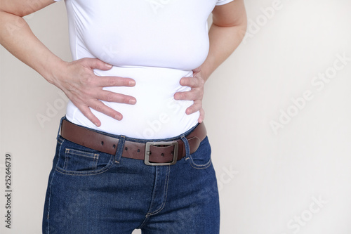 Pain area red background. A woman suffering from abdominal pain. Health problem. Woman holding hands on her stomach.