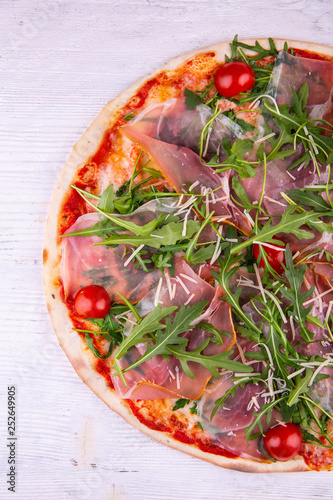 Pizza with a carbonate, arugula and cherry tomatoes