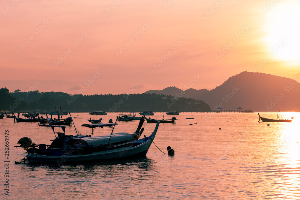 fishing boat in the sea in morning time with beautiful sunrise and reflection in the water at phuket andaman sea thailand