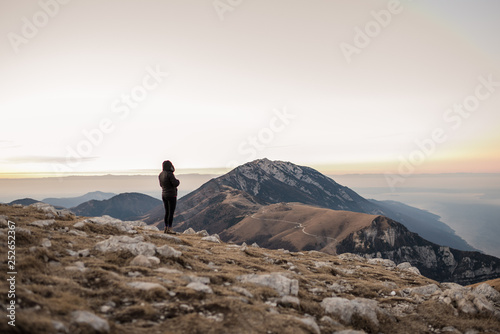 Donna in cima alla montagna guarda il panorama da sola, in Trentino photo