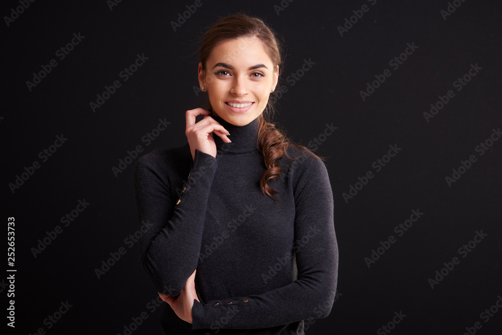 Attractive young woman studio portrait while standing at dark background Attractive young woman studio portrait while standing at dark background
