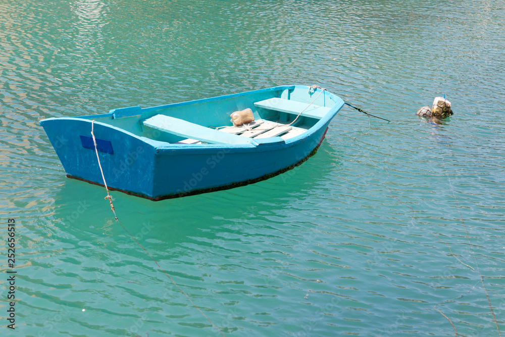 Fotografie Colorful blue traditional fishing boats in the green water in the harbor in Malt
