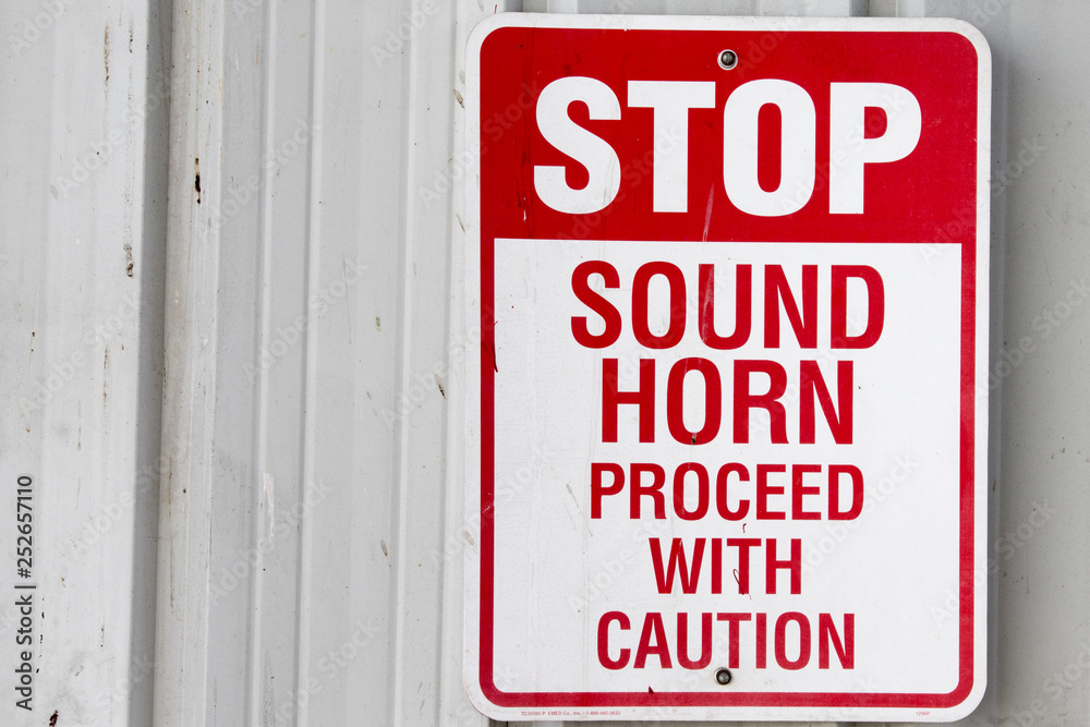 Red and white Stop sound horn proceed with caution sign on building Red and white Stop sound horn proceed with caution sign on building