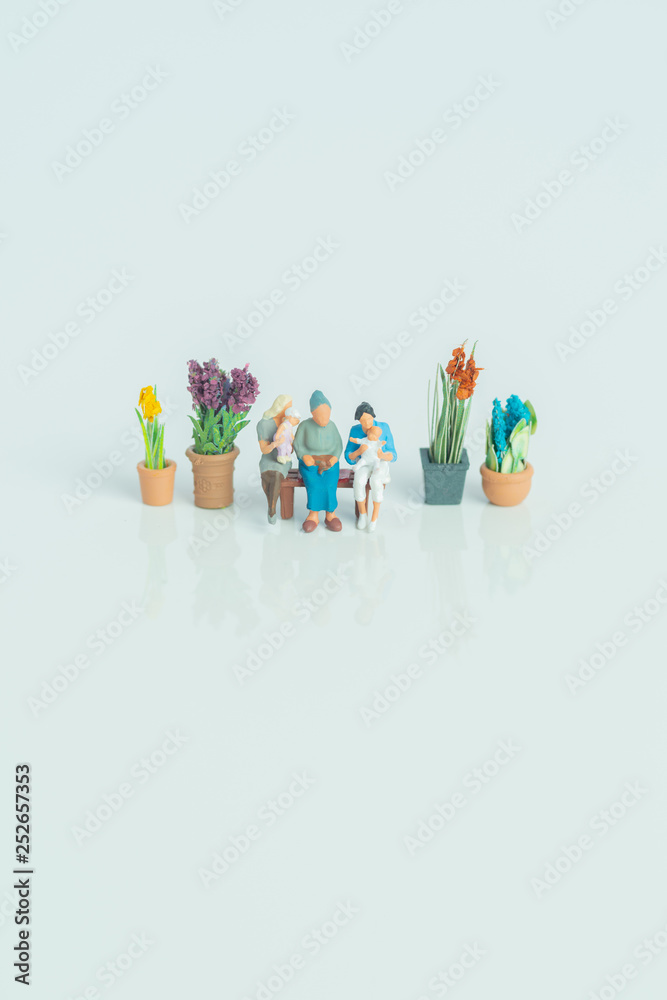 Miniature figurines - 3 generations of people on white background.