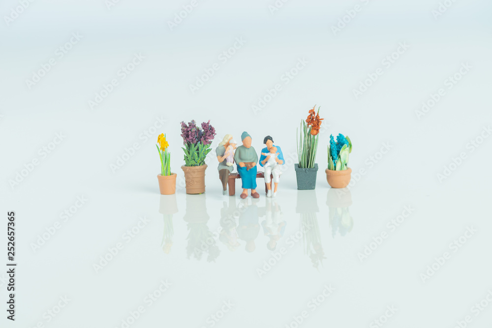Fototapeta premium Miniature figurines - 3 generations of people on white background.