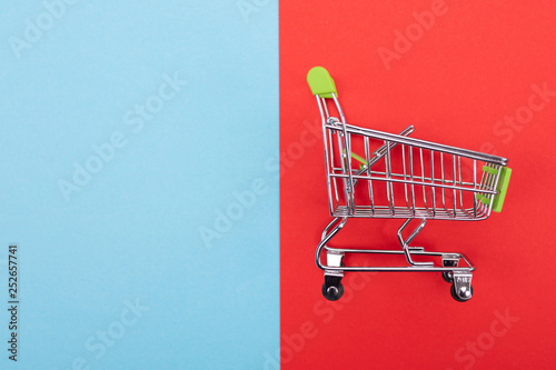 self-service supermarket trolley cart with green handle on colorful background photo