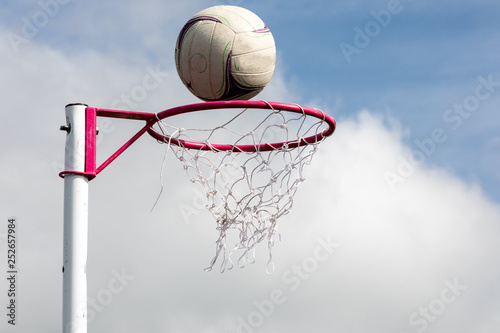 Netball post with ball about to go through the net photo