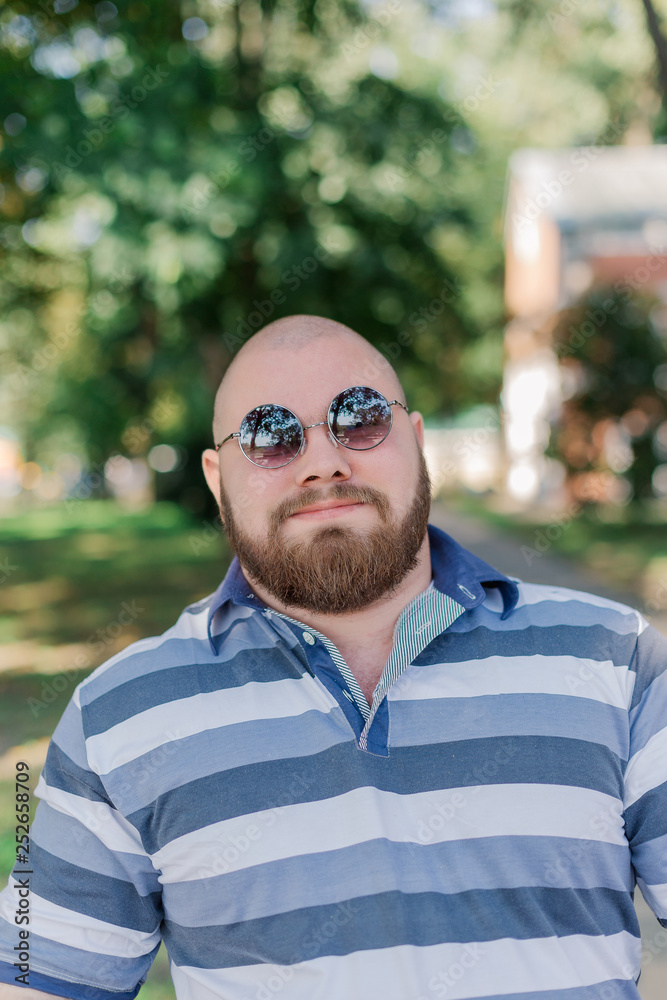 .Young man with round glasses and overweight in the park.