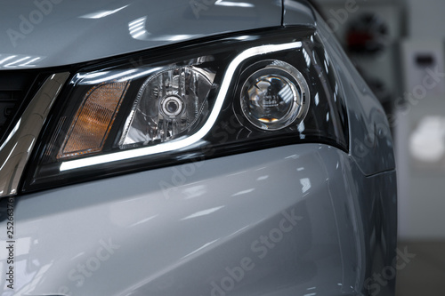 Closeup headlights of a modern car. Detail on the front light of a car. Modern and expensive car concept. The car is in the showroom