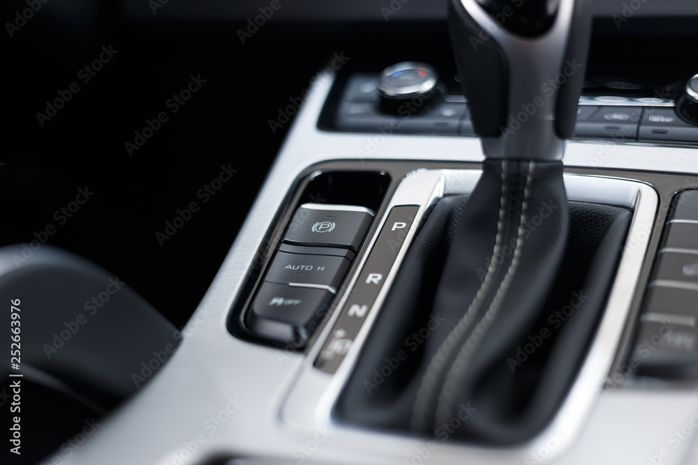 Selector automatic transmission with perforated leather in the interior of a modern expensive car. The background is blurred
