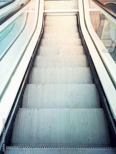 Descending escalator moving stairs in city shopping mall or business office building. Abstract concept of direction destination movement dynamics
