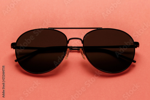Close-up sunglasses on coral background. Top view. Flat lay. Copy space. New minimal creative concept. Summer is coming concept. Living Coral color of the Year 2019
