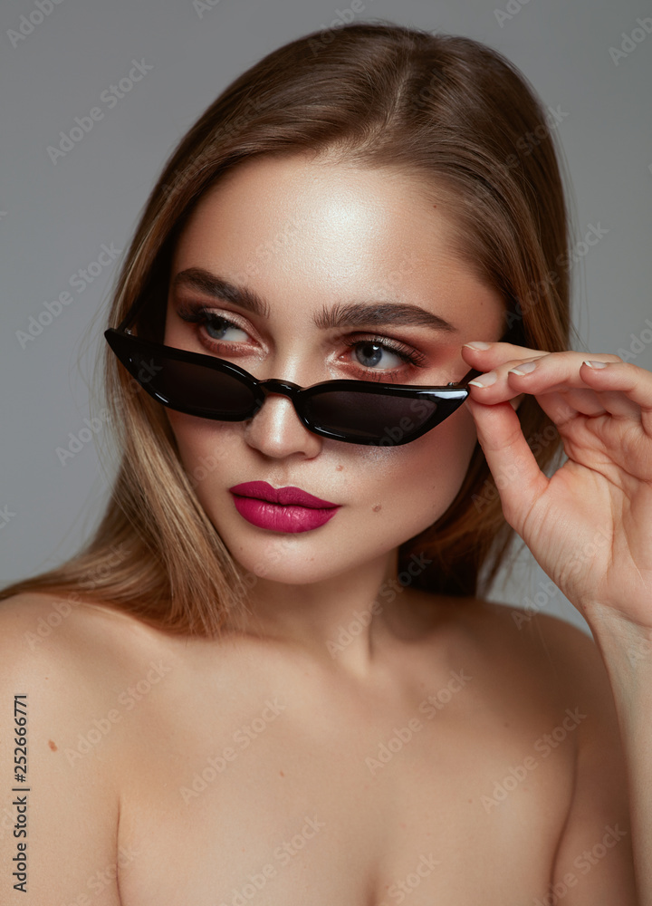 Close-up face of preatty young girl with big eyebrow wearing fashionable sunglasses Close-up face of preatty young girl with big eyebrow wearing fashionable sunglasses