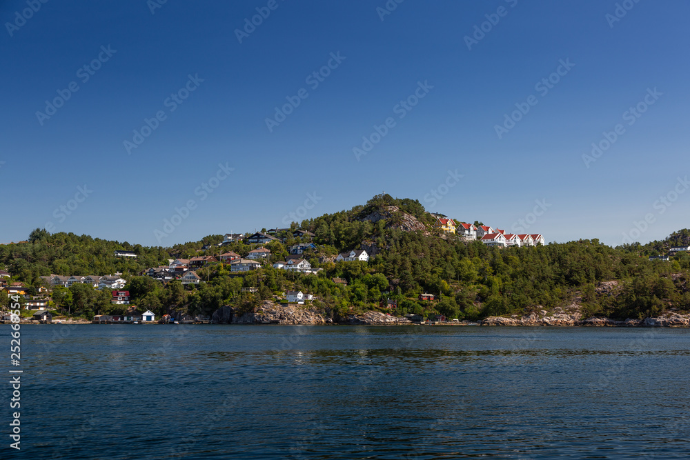 Norwegian coast from the sea. Green hills and houses