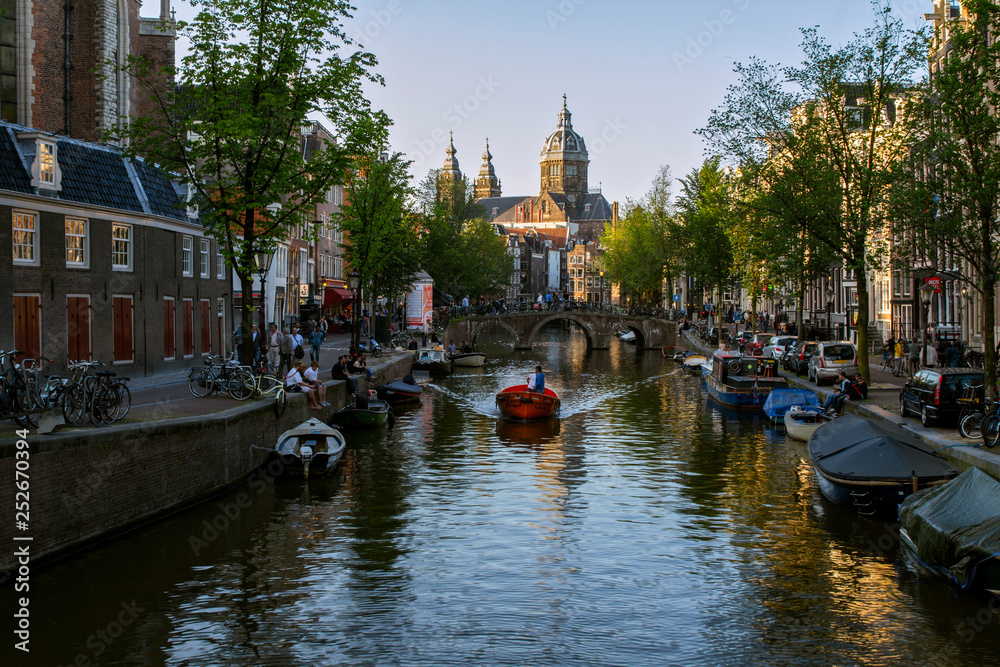 Fototapeta premium NETHERLANDS. On June 13, 2013. Beautiful view view of the Oude Church from the Oudezijds bridge of channels in the city center. Typical dutch houses. Amsterdam, Netherlands.